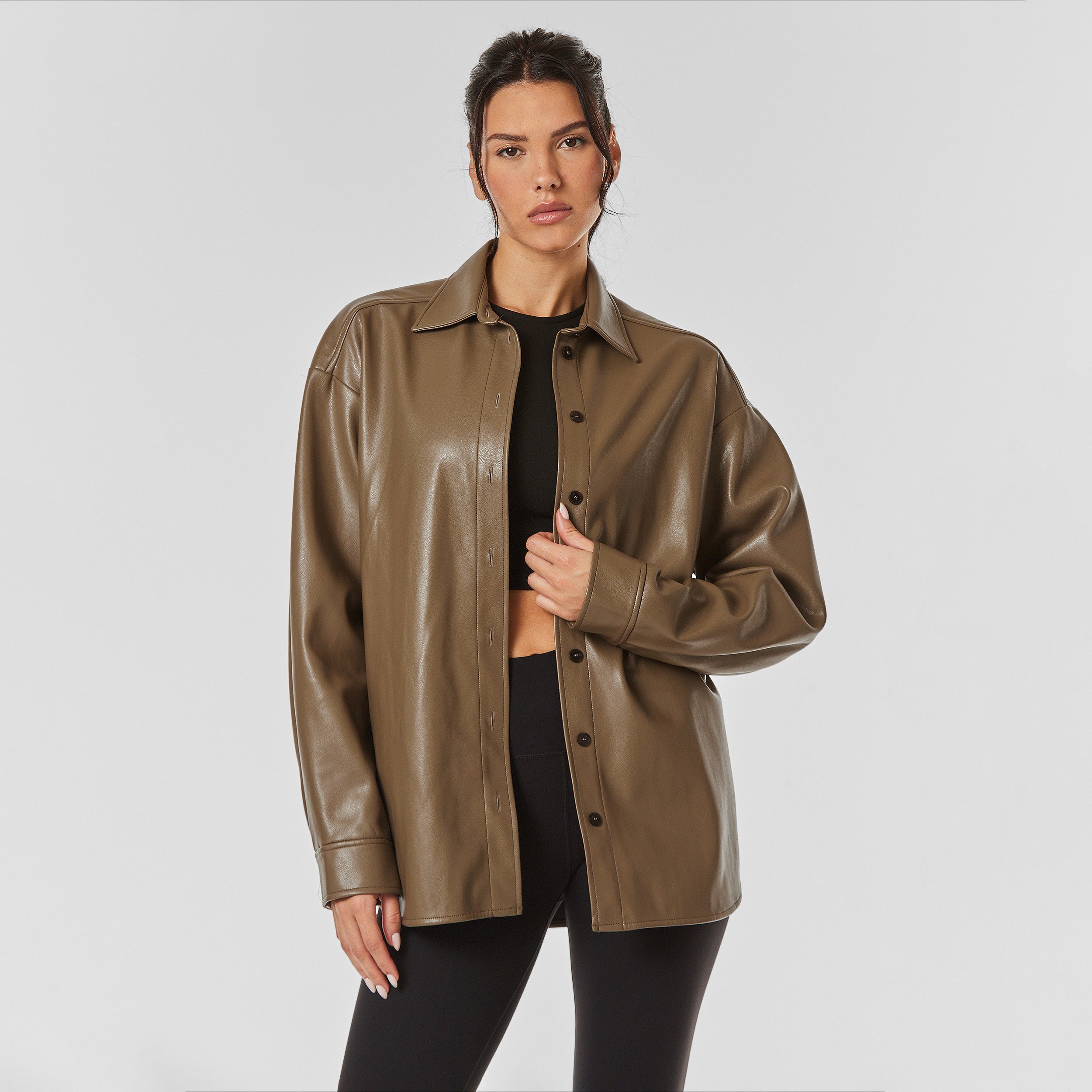 Front view of woman wearing brown faux leather oversized shirt jacket.