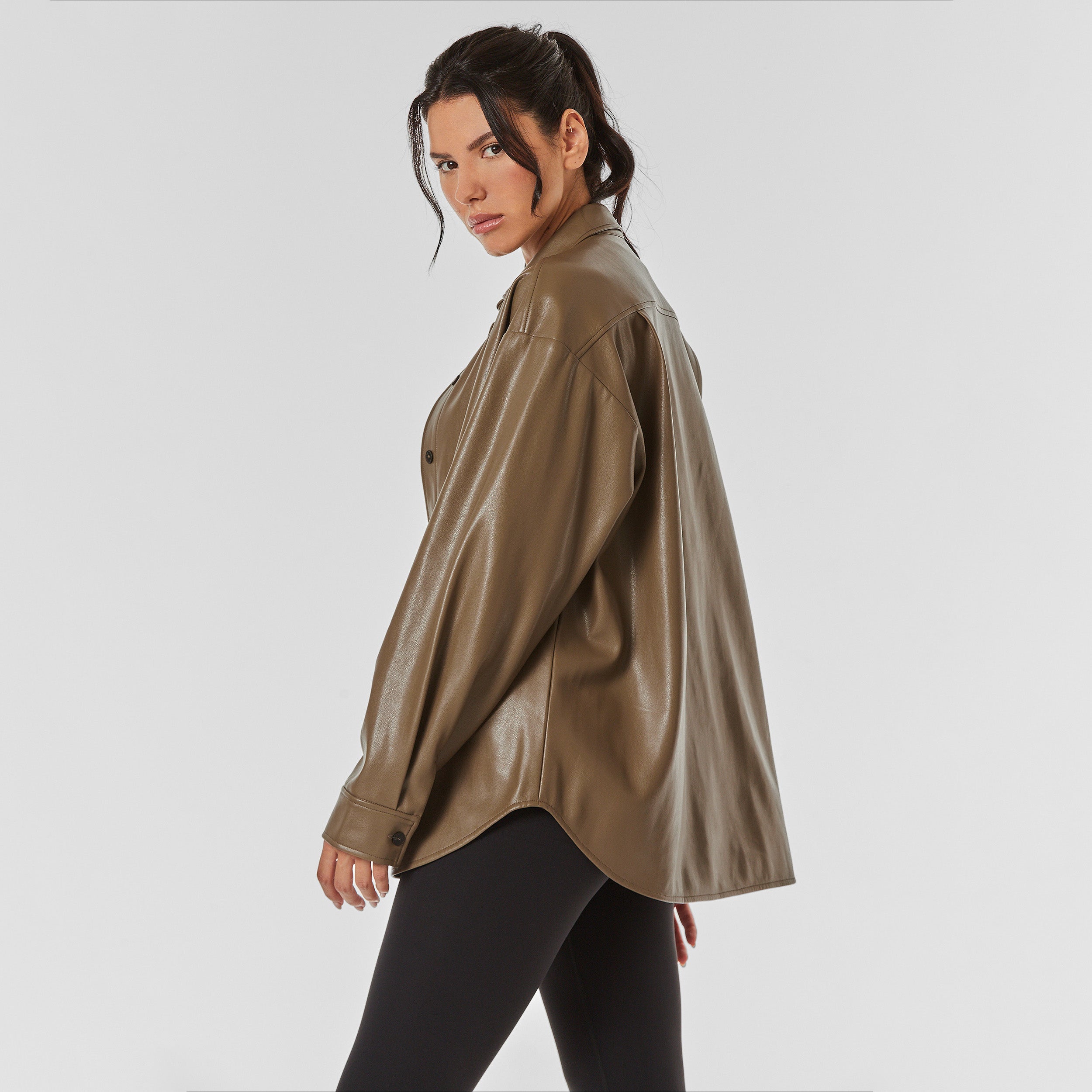 Side view of woman wearing brown faux leather oversized shirt jacket.