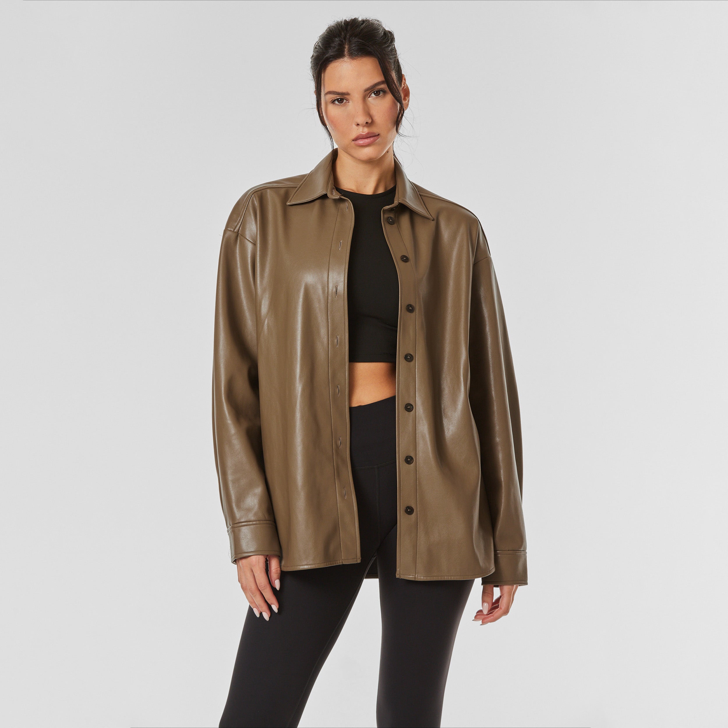 Front view of woman wearing brown faux leather oversized shirt jacket.