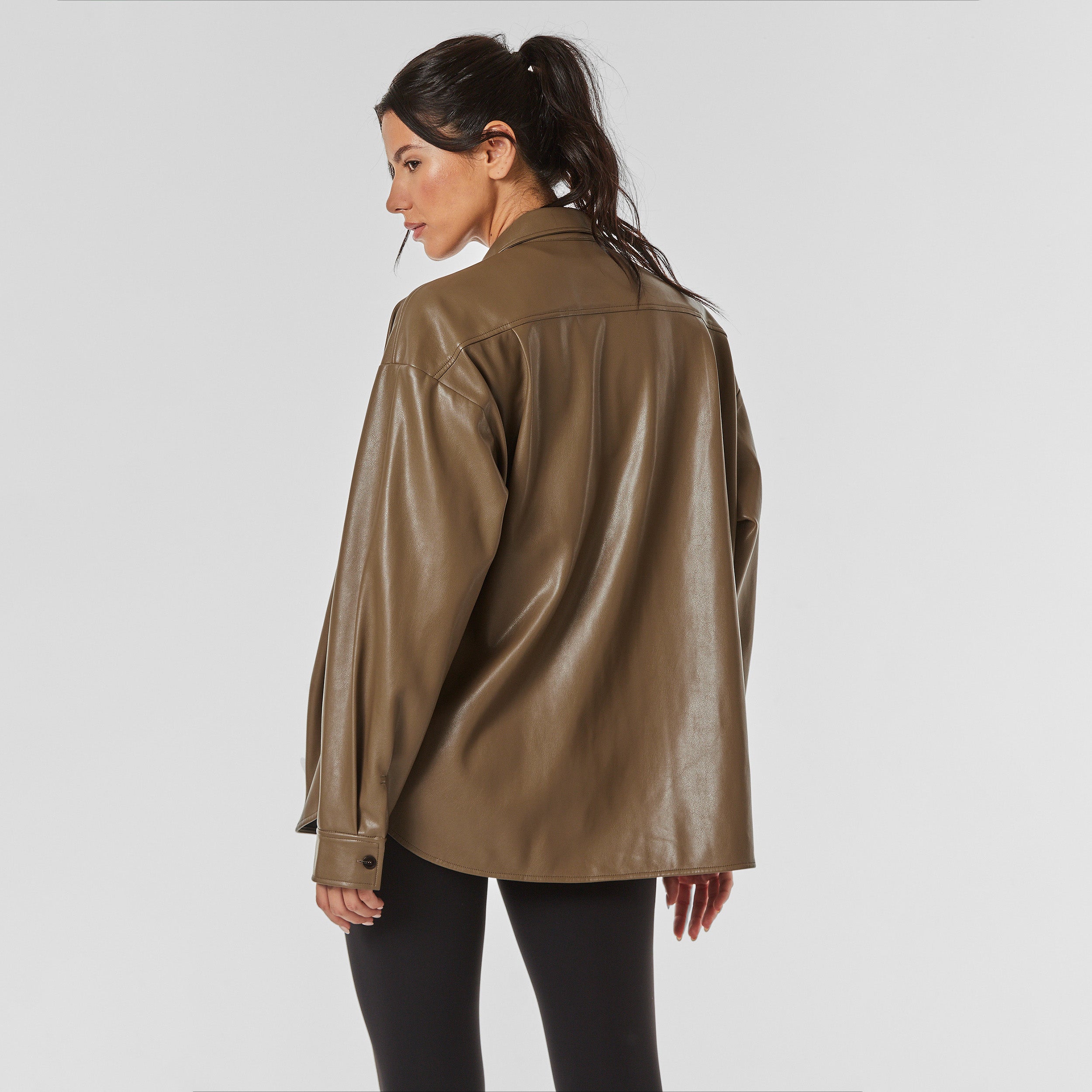 Rear view of woman wearing brown faux leather oversized shirt jacket.