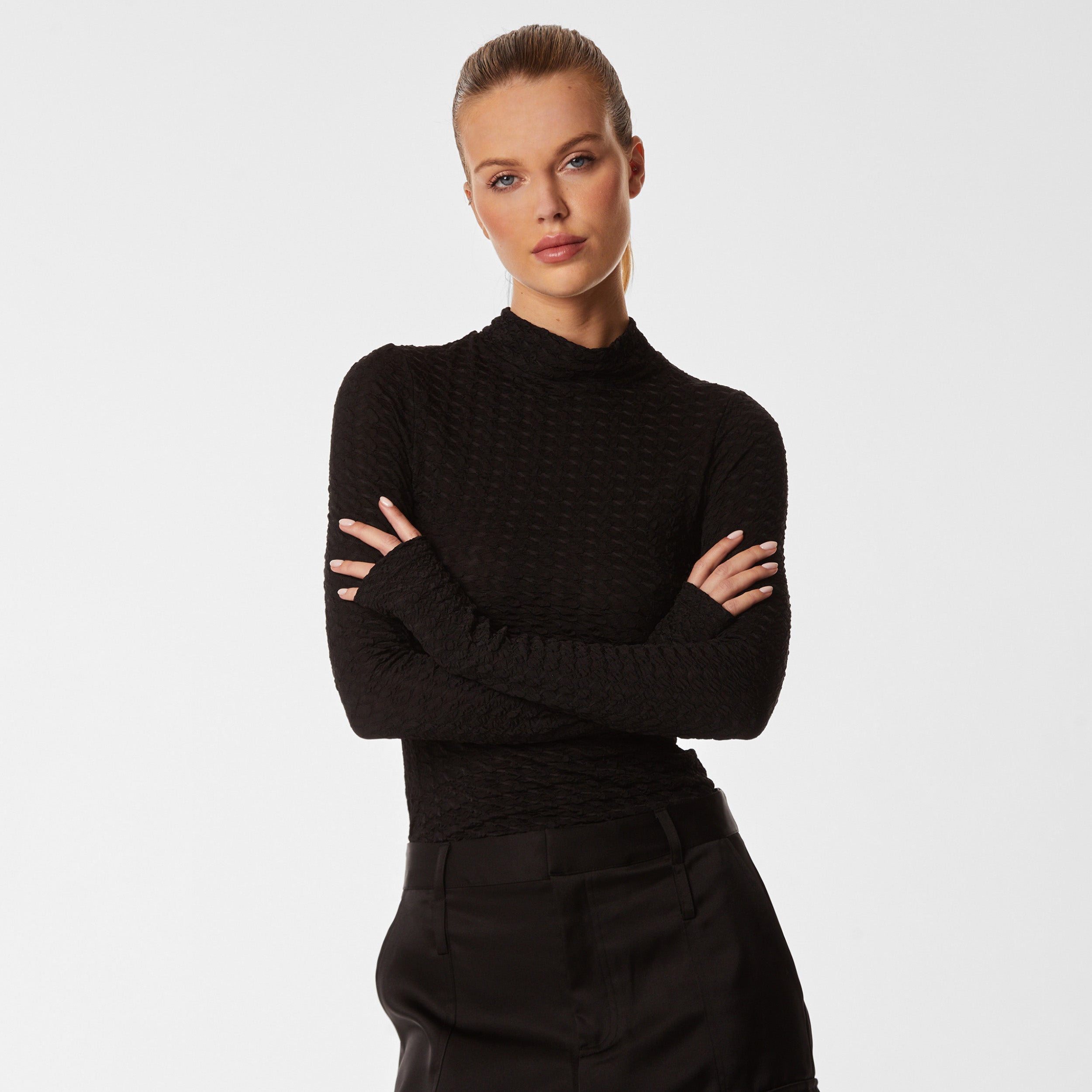 Woman wearing black stretch mesh textured turtleneck sweater