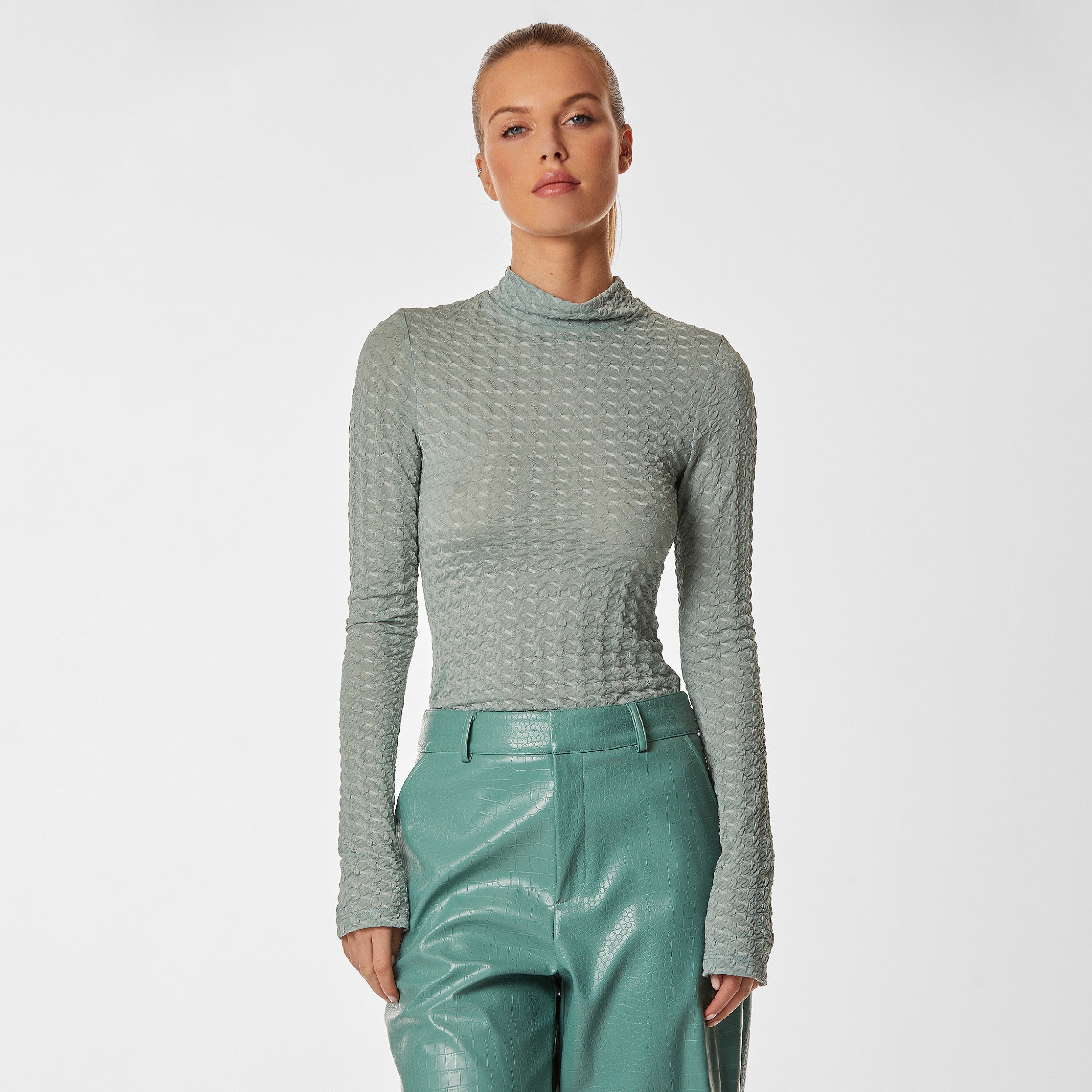 Woman wearing green stretch mesh textured turtleneck sweater