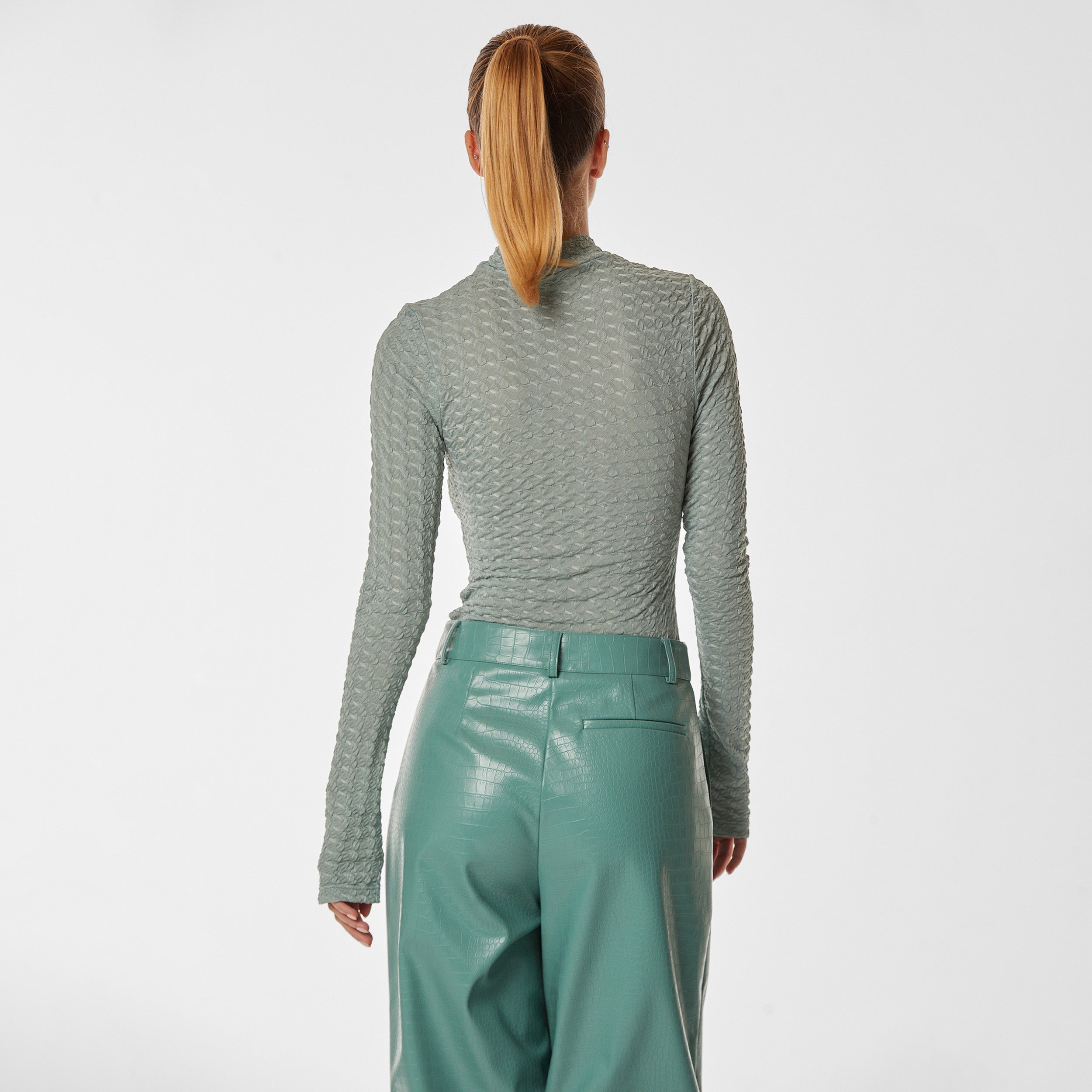 Rear view of woman wearing green stretch mesh textured turtleneck sweater