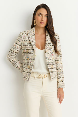 Woman with long, wavy hair and large hoop earrings stands against a white background wearing the Gabrielle Double Breasted Tweed Blazer in Ecru Multi, a white tank top, and high-waisted cream pants with a gold buckle belt.