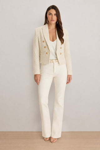 A woman faces forward in the Gabrielle Tweed Double Breasted Blazer - Beige, paired with a matching top, cream high-waisted pants, and nude heels, set against a plain light background.