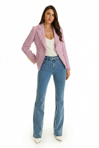 A woman with long brown hair and a neutral expression stands against a white background wearing the Giselle Single Breasted Tweed Blazer in blush, styled with a white top, blue flared jeans, and white pointed-toe shoes.