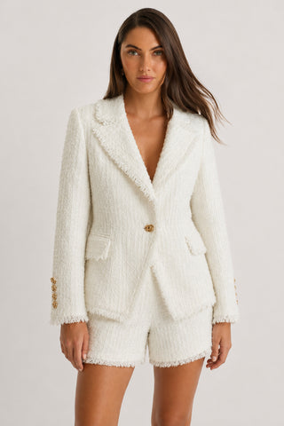 A woman wearing the Giselle Single Breasted Tweed Blazer in white, paired with matching white shorts, stands against a plain light background, embodying power dressing as she looks confidently at the camera.