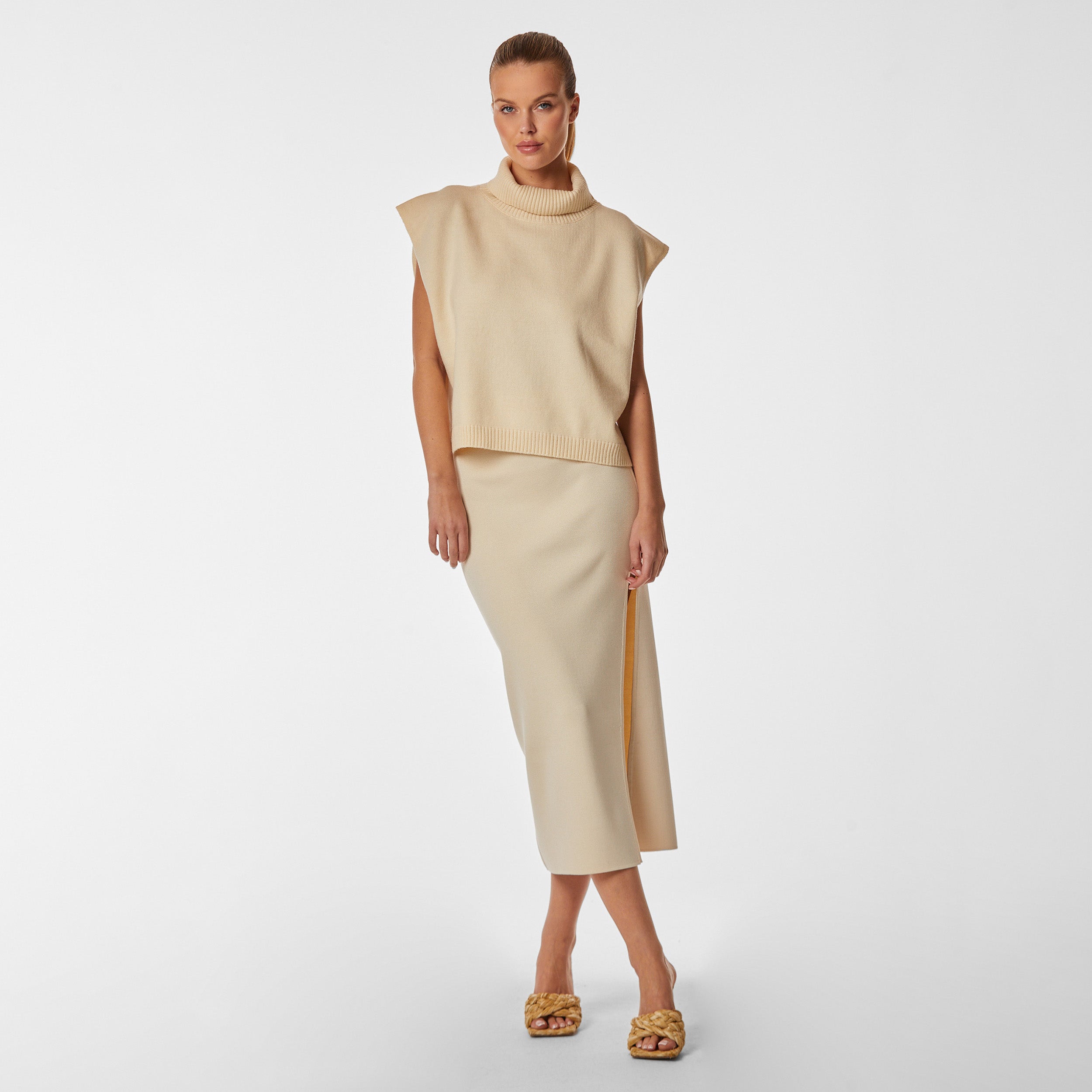 Full body front view of woman wearing sleeveless pearl sweater and pearl midi skirt