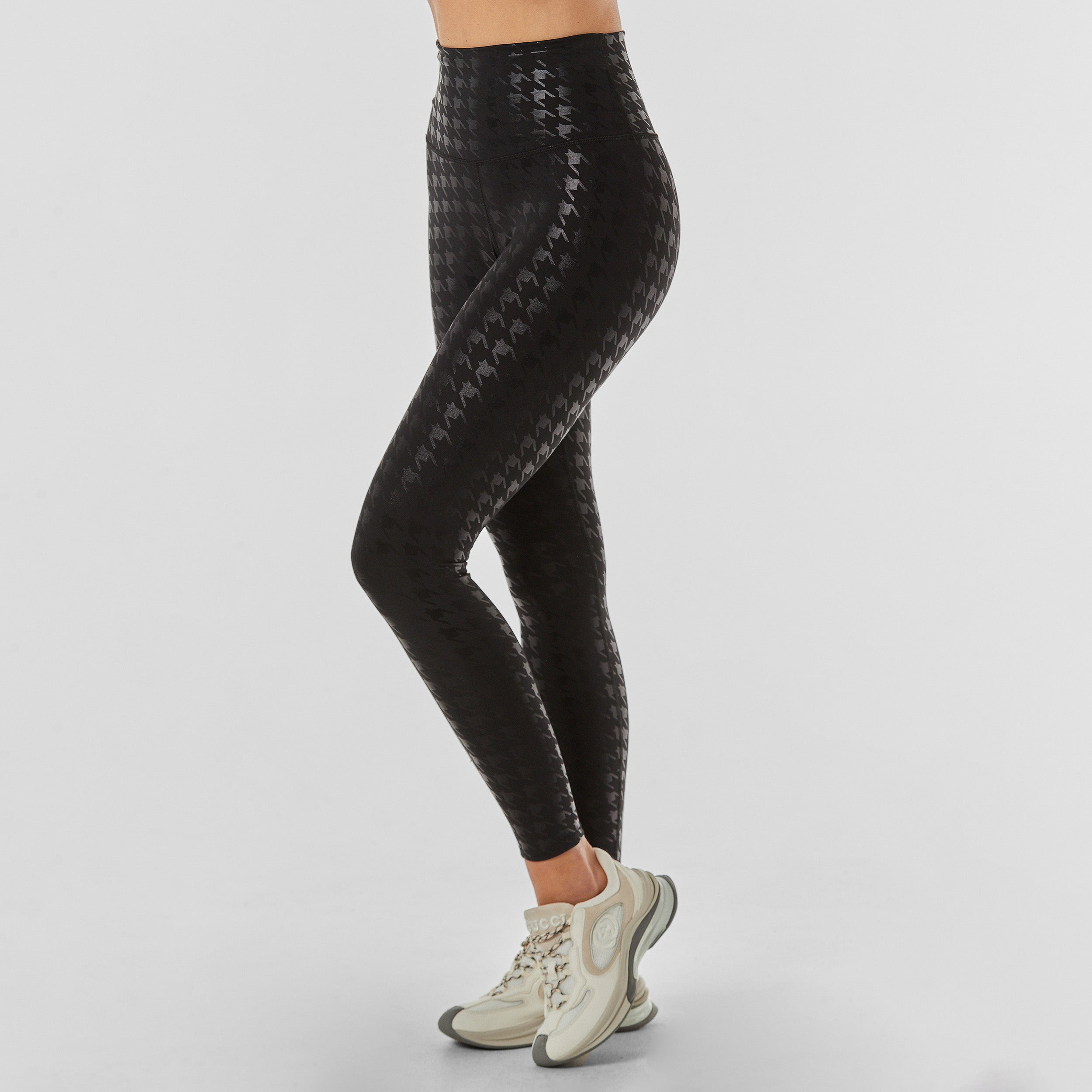 Side view of woman wearing black on black glossy houndstooth patterned legging