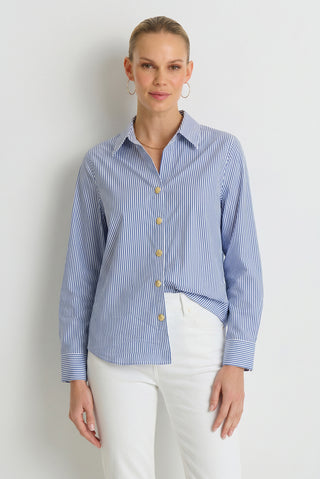 A woman wearing the Jasmine Shirt in blue stripe and white pants stands against a plain white background, looking at the camera with a slight smile.