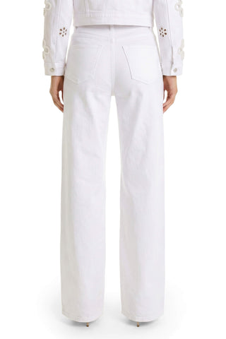 A person is shown from the back wearing the Kaia Pearl High Rise Jean - White, a wide-leg style featuring two back pockets, paired with a white jacket that has floral embroidery on the sleeves.