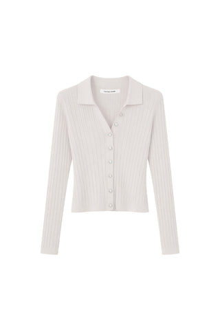 The Karolina Polo Shirt in white features a ribbed knit design, long sleeves, a V-neck with pointed collar, and button-down front—crafted from lightweight knitwear for comfort and style.