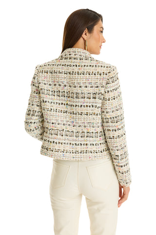 A woman stands facing away, looking right, in the Gabrielle Double Breasted Tweed Blazer - Ecru Multi—a structured blazer with a textured, multicolored grid pattern—paired with high-waisted cream pants.