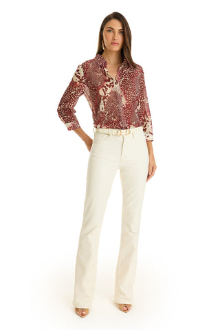 A woman stands facing forward in the Sara Chiffon Blouse - Garnet Crush, cream high-waisted belted pants, and open-toe heels against a white background.