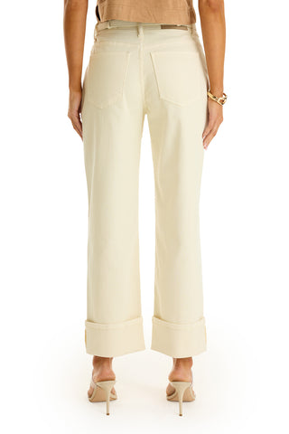 A person wearing the Ren Cropped Cuff Jean in Ivory and beige high-heeled sandals, shown from the back. The outfit is finished with a tan top and a gold bracelet.