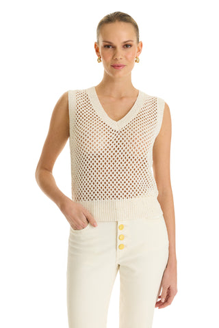 A woman wears the Addison Sequin Crochet Top - Pearl, a sleeveless cream knit with a V-neck, paired with high-waisted cream pants featuring gold buttons, standing against a white background and smiling slightly.
