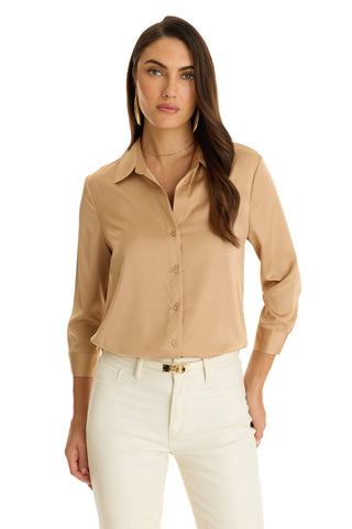 A woman with long brown hair stands facing forward against a plain white background, wearing the Sara Silk Blouse in Mocha with three-quarter sleeves, paired with white pants.