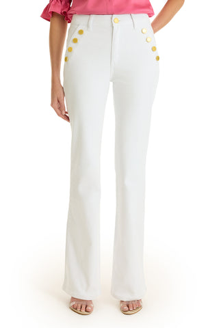 Wearing the Allegra Bootcut Jean in White featuring gold hip buttons, styled with a pink ruffled-sleeve top and open-toe heels, this cropped image from shoulders down exudes a chic vintage vibe.