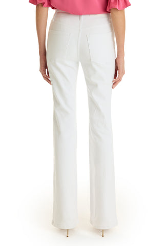 A person faces away, wearing the Allegra Bootcut Jean in white with back pockets, a pink ruffle-sleeve top, and beige heels. The clean white background highlights a vintage-inspired style.