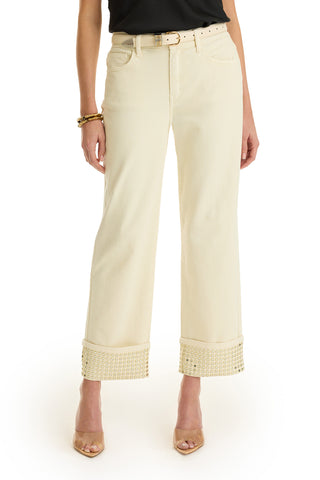 Wearing the Ren Cropped Cuff Jean - Gold Mirror, featuring cream four-way stretch denim, wide legs, and large embellished cuffs. Styled with a beige belt and nude heels. Only the lower half of the body is shown; top is black.