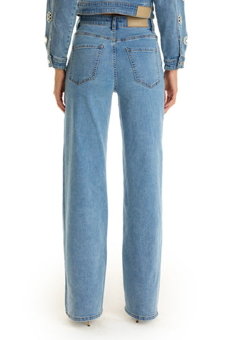 A person is shown from the back wearing the Kaia Pearl High Rise Jean in medium blue, styled with a matching denim jacket featuring decorative stitching on the sleeves.