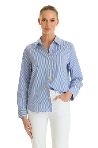 A person wearing the Jasmine Shirt - Blue Stripe with their left hand in the pocket of white pants, standing against a plain white background.