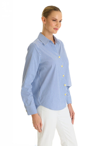 A woman with blonde hair tied back models the Jasmine Shirt - Blue Stripe, a long-sleeve stretch poplin shirt, paired with white pants and set against a plain white background.