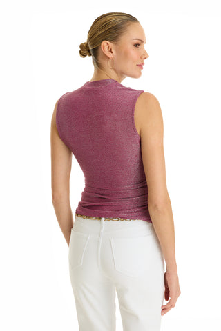 A woman with blonde hair in a bun wears the Mia Shimmer Tank in amethyst and white pants with a gold chain belt, standing and facing slightly away against a white background.
