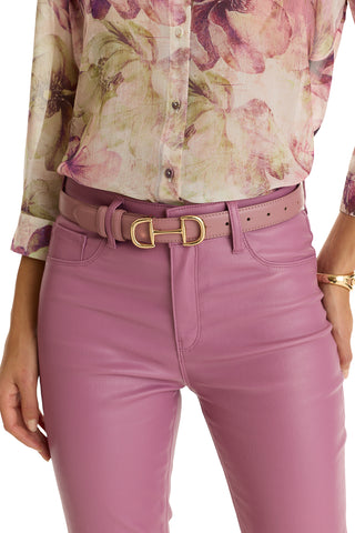 A person wearing high-waisted mauve leather pants, a Bettie Belt - Mauve with a gold double D buckle, and a sheer floral blouse in pink, purple, and green.