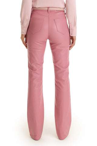 A person stands with their back to the camera, wearing high-rise Aria Coated Flare Jean in Paradise Pink and a matching long-sleeve shirt with buttoned cuffs.