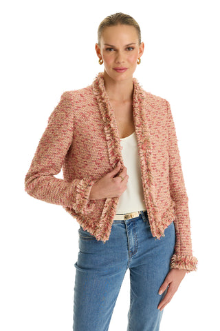 A woman stands against a white background wearing the Florence Tweed Jacket - Rose Multi with a fringe hem over a white top and blue jeans, holding the jacket lapel with one hand.