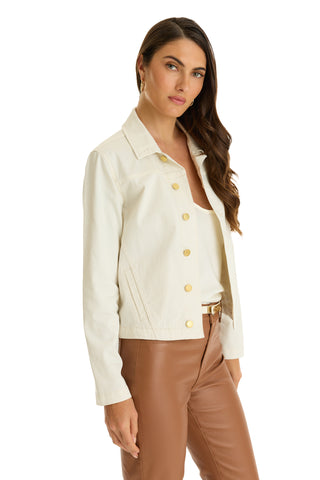 A woman with long brown hair models the Joelle Jean Jacket in ivory over a white top and light brown leather pants, standing against a white background.