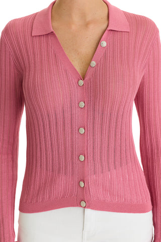 Wearing the Karolina Polo Shirt in Petal Pink—a ribbed, lightweight knit with shiny diamond buttons, collar, and a slightly sheer texture—paired with white pants.