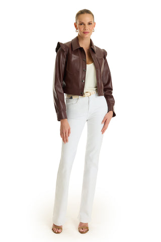 A woman poses against a white background in the Chantal Ruffle Sleeve Leather Jacket - Espresso, paired with a white top, white jeans, beige belt, open-toed sandals, hoop earrings, and her hair pulled back for a chic fall statement look.