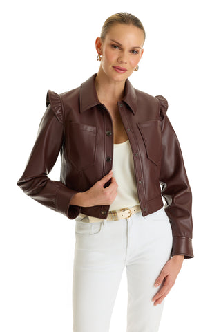 A woman wears the Chantal Ruffle Sleeve Leather Jacket - Espresso with a white top, white pants, and a beige belt, posing against a white background—a perfect statement piece for fall.