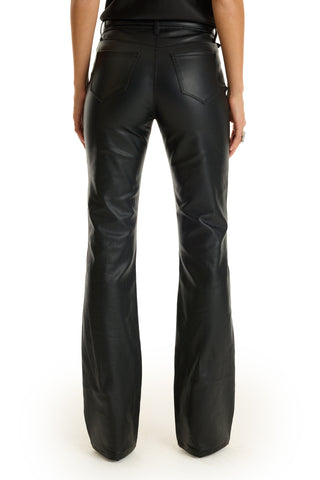 A person is shown from the waist down, facing away, wearing the Aria Coated Flare Jean in black with a high-rise fit and slim bootcut legs, against a white background.