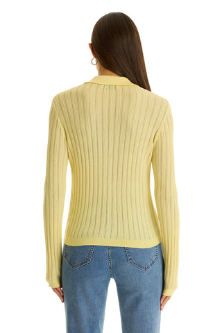A person with long, straight brown hair is seen from the back in the Karolina Polo Shirt - Sunshine Yellow and blue jeans—an effortless nod to spring fashion.