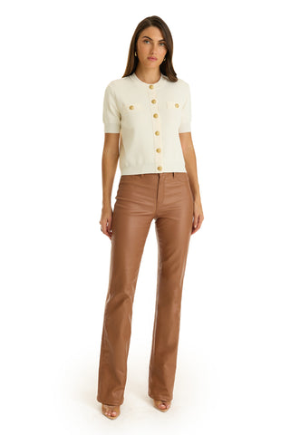 A woman faces forward against a white background, wearing the Bonnie Knit Cardigan Top in pearl with padded shoulders and buttons, paired with high-waisted brown wide-leg pants and open-toe shoes.