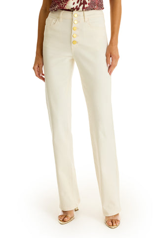 Someone styled in the Aubrey Bootcut Jean - Ivory, featuring a high waist and gold buttons, pairs it with open-toe heels and a patterned top.