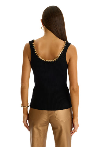 A woman with long, straight brown hair wears the Millie Knit Tank - Black with a gold chain neckline detail, paired with tan leather pants. She is seen from the back against a white background.