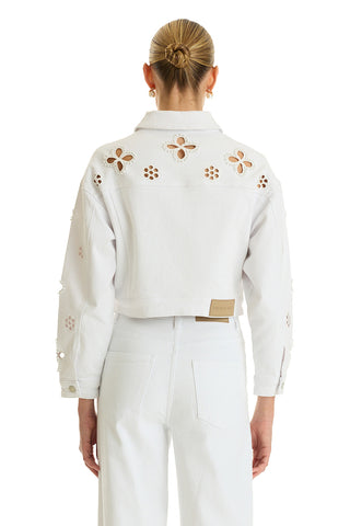 A woman with blonde hair in a neat bun is seen from the back wearing the Kaia Pearl Jean Jacket in white, styled with matching white pants.