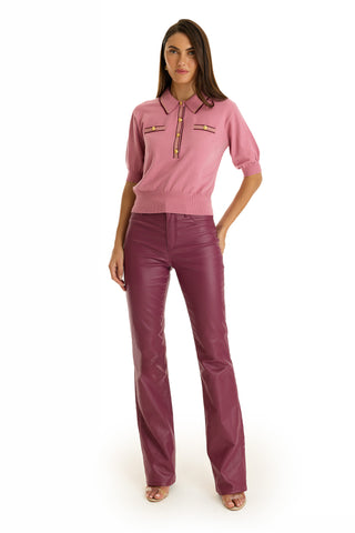 A woman stands against a white background wearing the ultra-soft knit Bobbi Polo Shirt in Dusty Rose with pocket details, paired with high-waisted burgundy leather pants, long hair, and nude open-toe heels for an elevated casual look.
