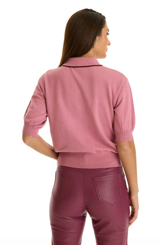 A woman faces away from the camera, sporting the ultra-soft knit Bobbi Polo Shirt in Dusty Rose and high-waisted maroon pants against a plain white background, showcasing elevated casual wear.