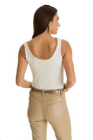 Woman with long brown hair facing away, wearing the Millie Knit Tank - Pearl featuring a gold chain detail at the neckline, large gold hoop earrings, and beige belted pants. White background.