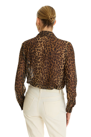 A person with blonde hair in a neat bun wears the Ana Chiffon Blouse - Leopard and high-waisted white pants, shown from the back against a white background.