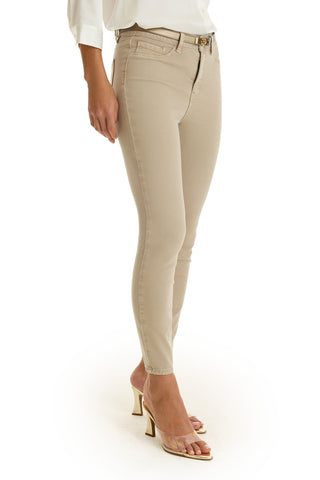 Wearing the Nina Cropped Skinny Jean in Oatmeal, a white long-sleeve shirt, and clear high-heeled sandals, the person stands against a plain white background with their face not visible.