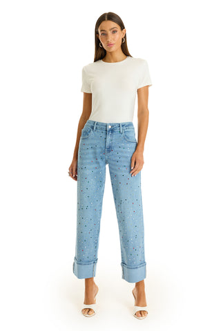 A woman stands facing forward in a fitted white short-sleeve shirt, Ren Cropped Cuff Jean - Confetti with a rainbow gem finish and four-way stretch denim, and open-toe heels, against a plain white background.