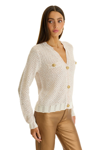 A woman wears the Shannon Sequin Cardigan Top in Pearl with tan leather pants, standing against a white background.