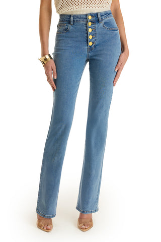 A person wearing Aubrey Bootcut Jean in medium blue with a sleeveless knitted top, chunky gold bracelet, and clear heeled sandals. Photo is cropped at the shoulders.