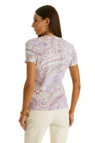 A woman with straight brown hair stands with her back to the camera, showcasing the Amaya Ultra-Soft T-Shirt in Pastel Paisley and cream pants for a stylish look.